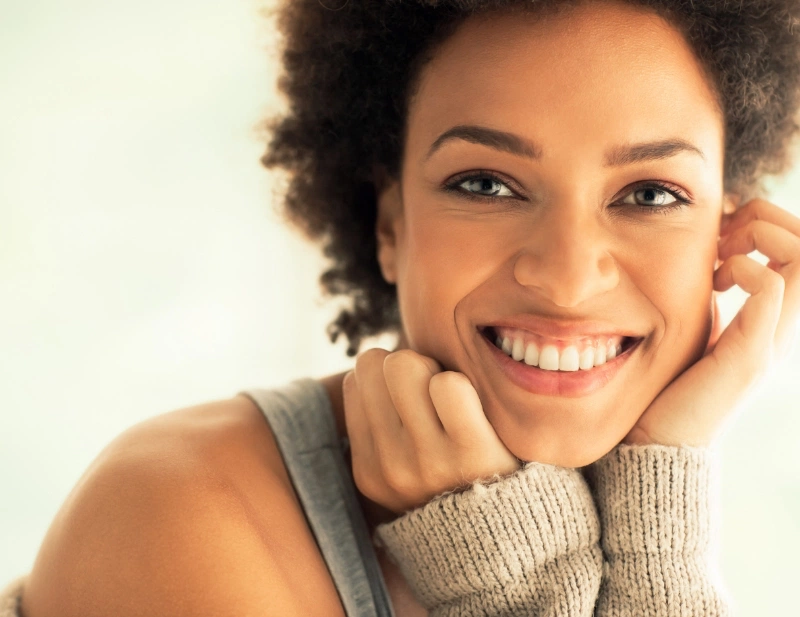 Portrait of black woman holding hands to her face and smiling