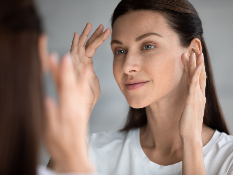 woman with youthful skin looking in the mirror