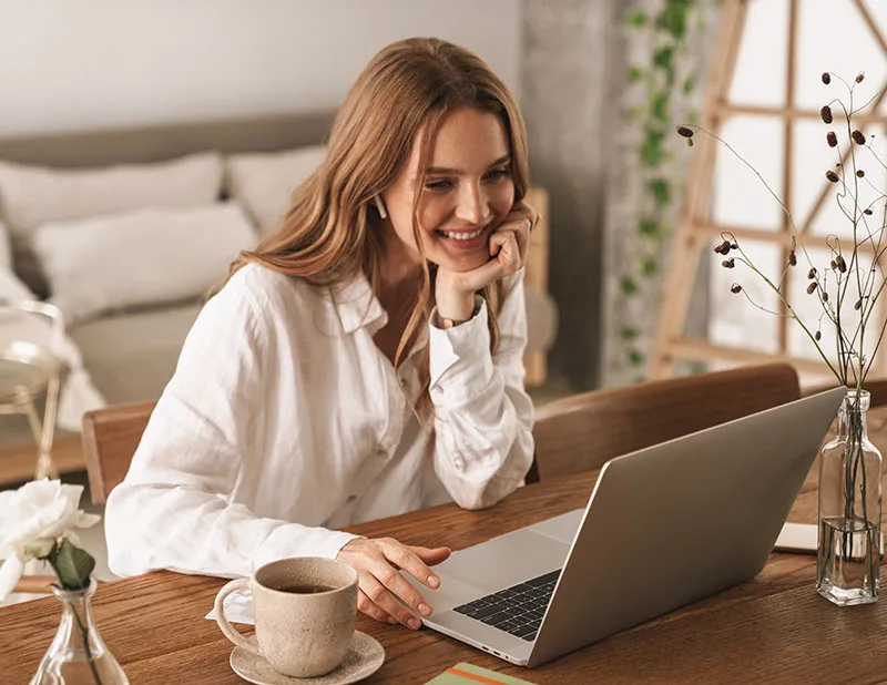 happy woman sitting indoors using laptop