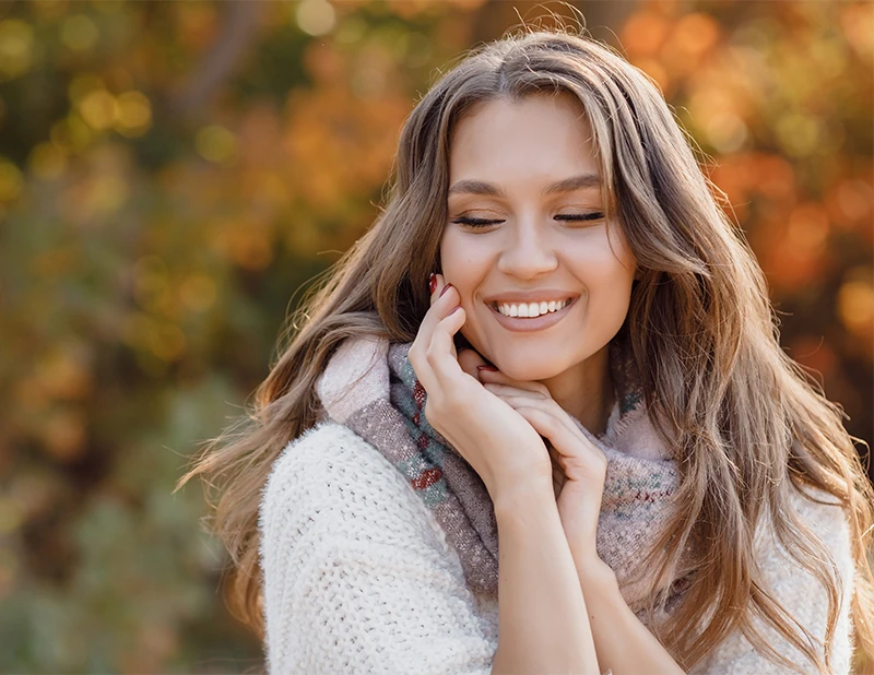 Beautiful woman wearing scarf outside and touching her face