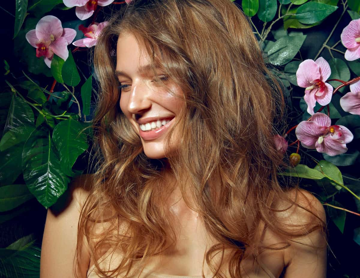 woman with glowing youthful skin surrounded by flowers