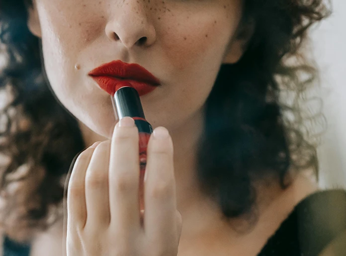 WOMAN PUTTING LIPSTICK ON IN THE MIRROR