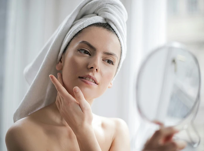 beautiful woman looking at her skin in the mirror